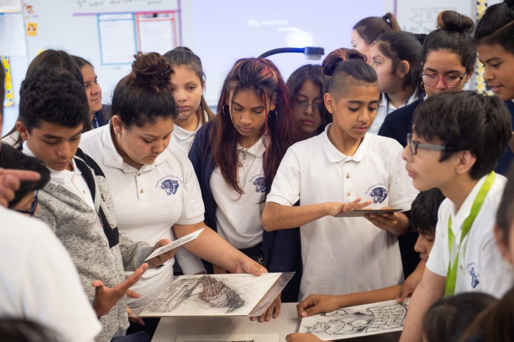 group of students examine art prints