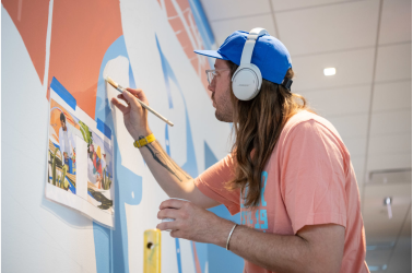 small version of CERA painting a coporate mural