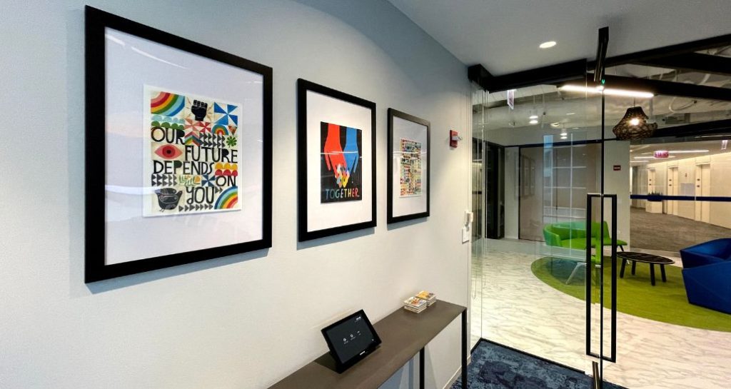 A sleek office with brightly coloured prints haning on the walls. This mini art gallery inside the office, provides a point of focus and helps to inject colour into a neutral space. This art rental collection from ipaintmymind helps this workspace stand out.